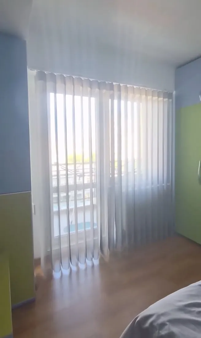 Jaluzele verticale din material textil la o ușă de balcon